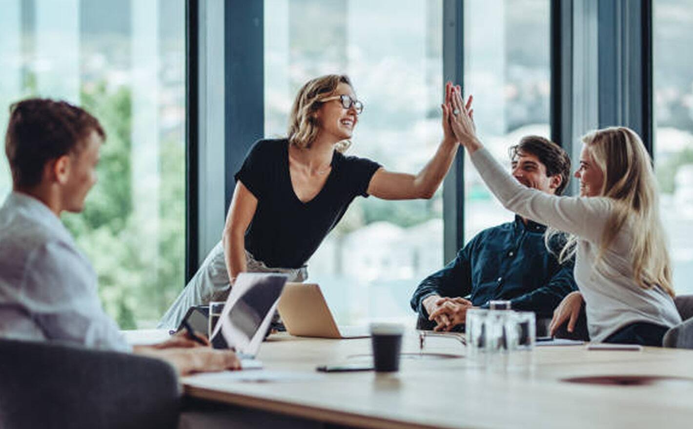 A group of business professionals exchanging high fives in a meeting