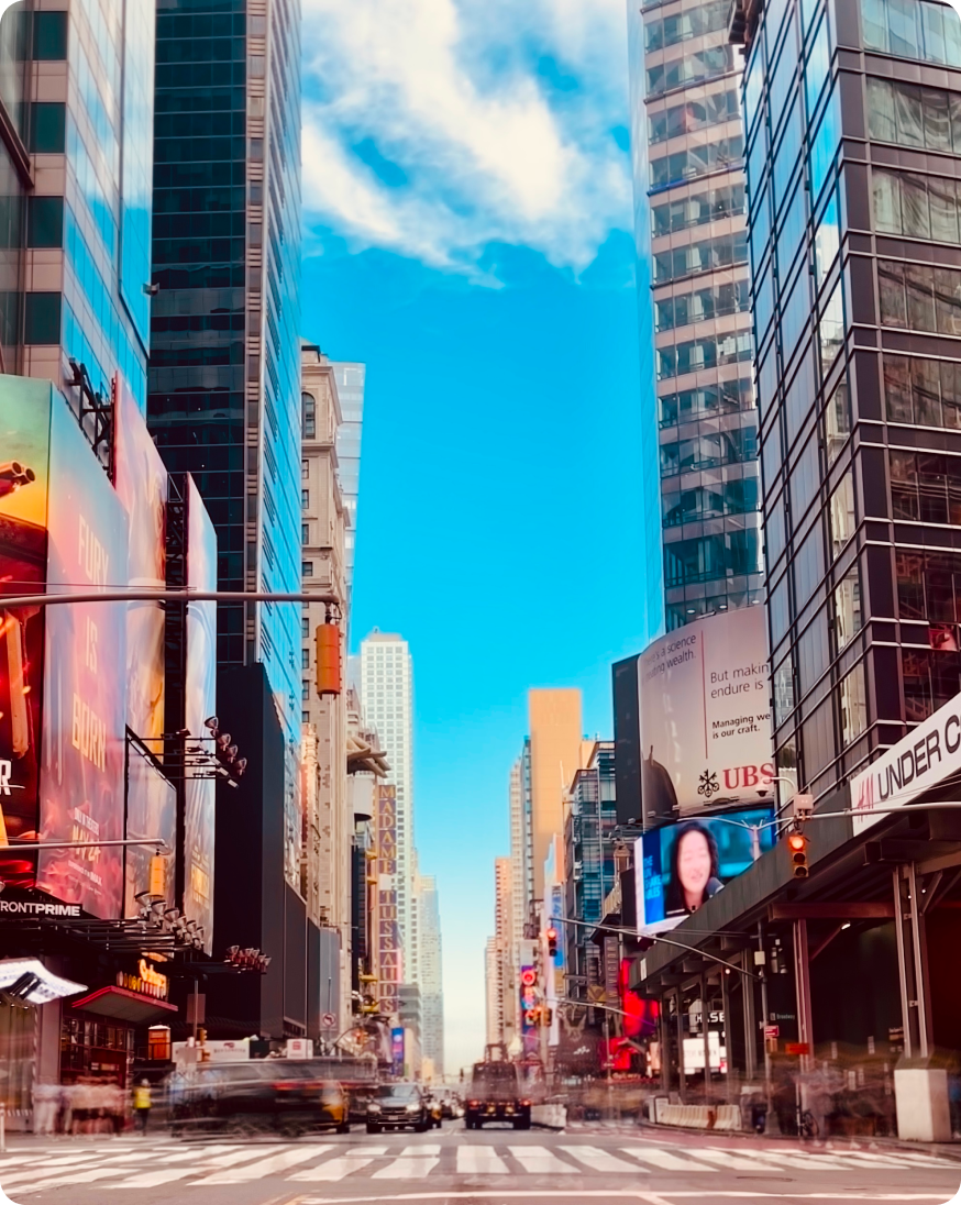 A city street scene with towering buildings and large billboards.